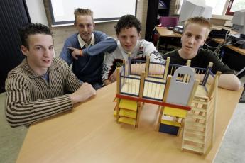 Geert Wols, Rolf de Raaf, Martijn Koedood en André Herweijer bij de maquette van het speelwerkhuisje dat zij bouwden.