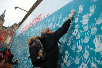 Een meisje plaatst een handafdruk op de blauwe muur.