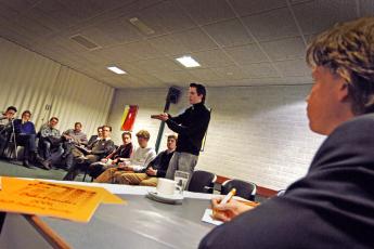 Trainer Ronald van Bruchem (r.) luistert naar het debat.