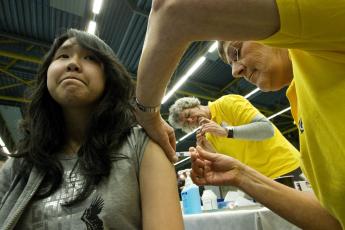 Een meisje wordt in een sporthal in Helmond ingeënt.
