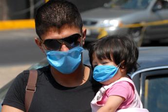 Een man en zijn dochtertje beschermen zich tegen besmetting met de Mexicaanse griep.